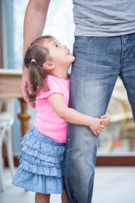 Side view of girl hugging father's leg in house