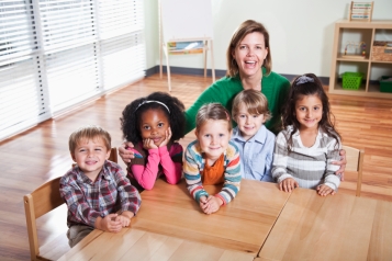 Preschoolers with teacher sitting at table in classroom