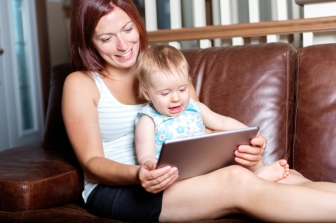 mother and baby are looking to play and read tablet computer on the couch at home