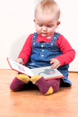 young baby girl happily reading a book