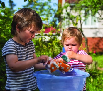 Children washing the dishes outdoors