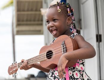 Smile african girl play guitar with happy feeling at outdoor terrace house.