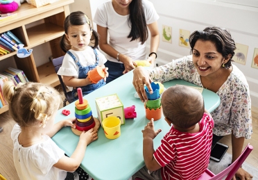 Nursery children playing with teacher in the classroom