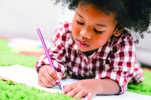 Cute young African American kid girl drawing or painting with colored pencil. Kindergarten children education, or preschool child study at home concept