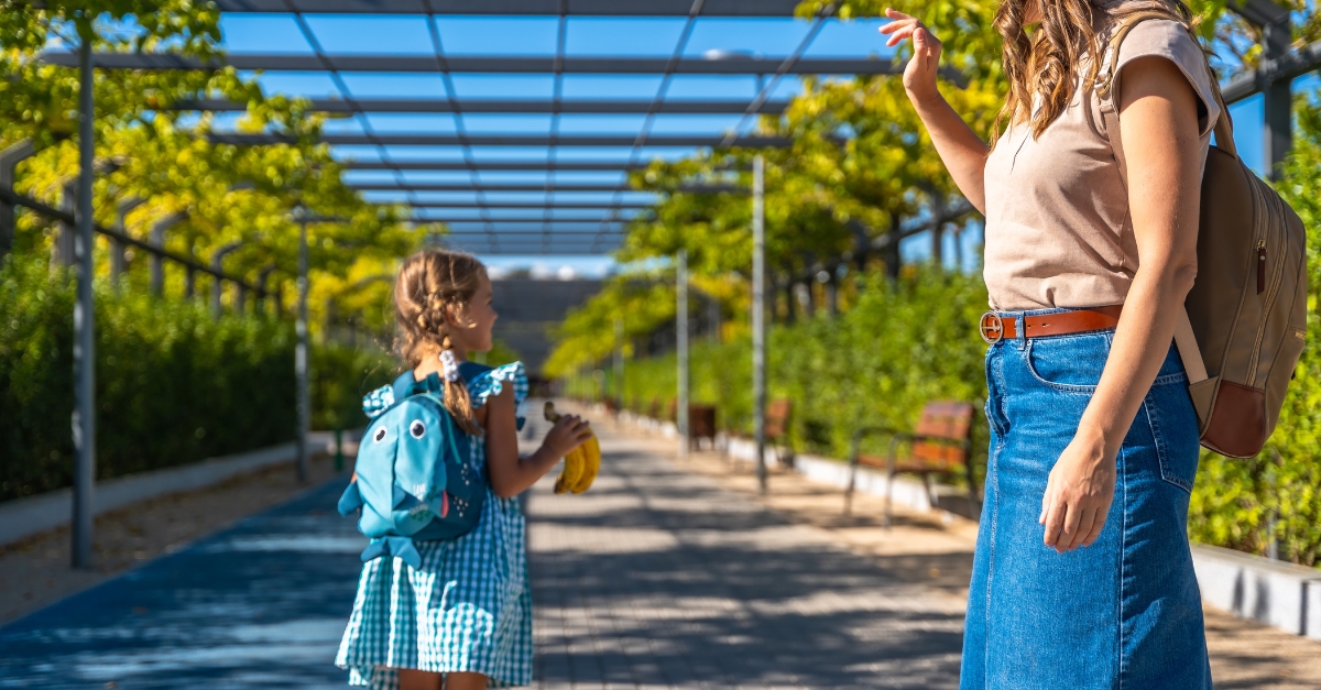 Parent waving goodbye to a preschooler as they drop them off for school