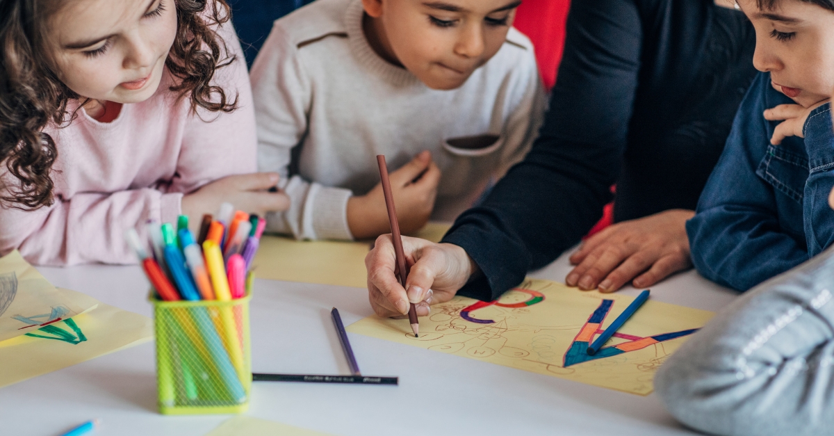 Preschoolers watching their teacher draw letters and lead a lesson
